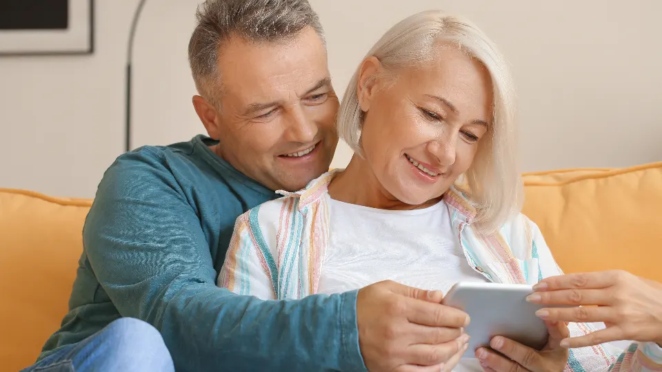 Casal sentado no sofá olhando juntos a tela de um tablet